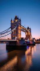 Obraz premium Tower Bridge at dusk, showcasing stunning architecture and reflections in water. beautiful scene of London illuminated by evening lights