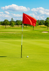 Obraz premium Summer Outdoor Golf Tournament with Red Flag on Fresh Turf. National Golf Day