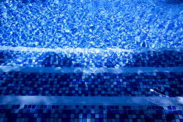 Blue mosaic tiles under the swimming pool create a shimmering reflective pattern.