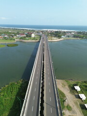 Obraz premium Special Region of Yogyakarta, Indonesia - September 3, 2025 : A Scenic Bridge Spanning a Wide River with Lush Green Surroundings