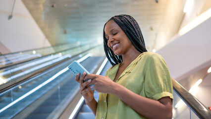 Businesswoman using smartphone on escalator in modern building