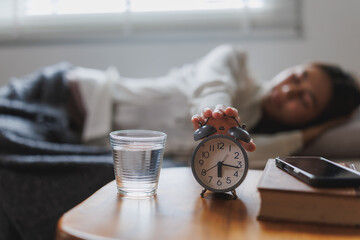 Woman turning off alarm clock early morning