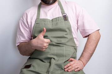 A man in a kitchen apron. Chef work in the cuisine. Cook in uniform, protection apparel. Job in food service. Professional culinary. Green fabric apron, casual stylish clothing. Handsome baker posing
