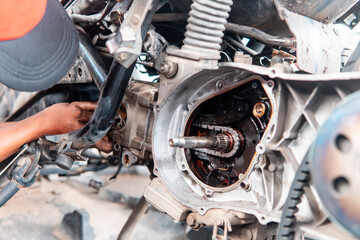 Fototapeta premium Close-up of a mechanic repairing a motorcycle engine with bare hands in a workshop. Concept of maintenance, manual skill, automotive repair, vehicle service, and industrial work. 