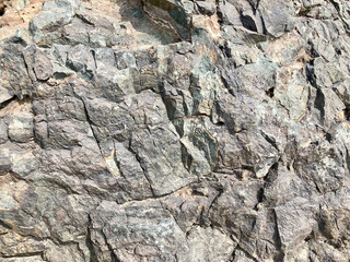  close-up perspective of a naturally weathered stone formation. The rugged, detailed surface displays a tapestry of colors and textures