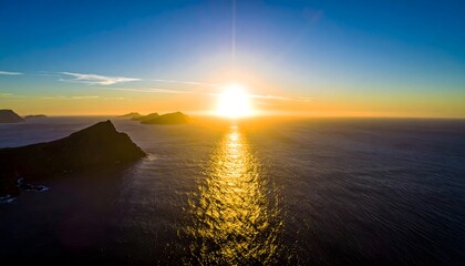 Dramatic golden sunset over vast ocean, illuminating a shimmering path towards silhouetted coastal mountains
