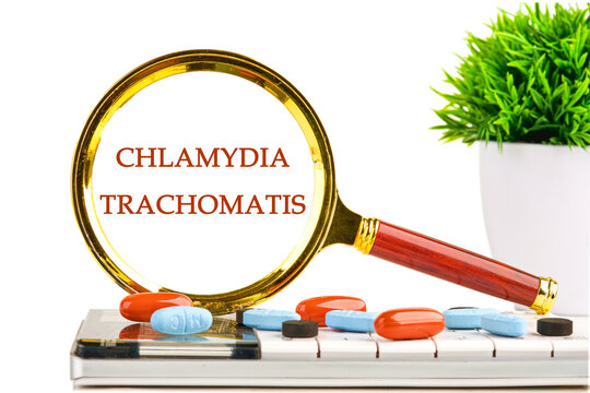 Chlamydia trachomatis through a magnifying glass on a white background on a calculator with a green plant and tablets, vitamins