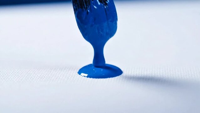 Artist's brush applying a thick dab of rich blue paint onto a fresh white canvas