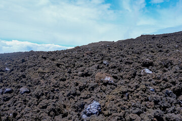 Rugged volcanic lava field under a bright sky, showcasing hardened black rocks, unique textures, and the raw aftermath of an eruption, a breathtaking geological landscape