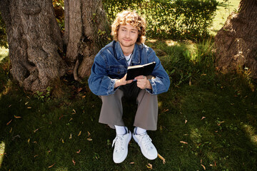 Handsome man enjoys quiet moment reading in a sunny park surrounded by nature