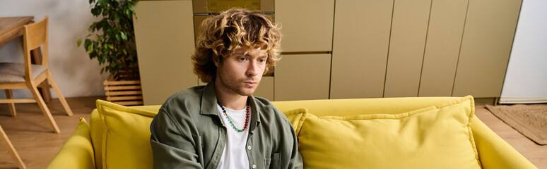 Obraz premium Handsome man relaxing on bright yellow couch in cozy modern living room setting