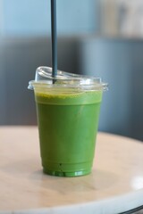 Green tea in a clear plastic cup Placed on table.