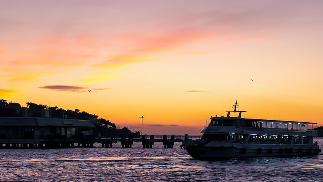 Dramatic sunset over sea light reflecting in water surface ferry boat silhouette