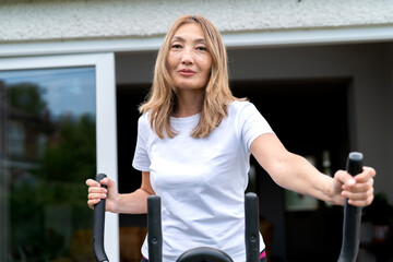 Woman exercising on elliptical machine at home in the morning, showcasing fitness routine and healthy lifestyle