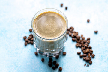 Matcha Latte in a Glass with Coffee Beans on a Blue Background