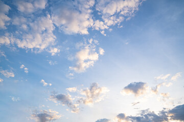 White fluffy clouds float gently in a clear blue sky on a bright sunny day. The scene feels open clean and refreshing.