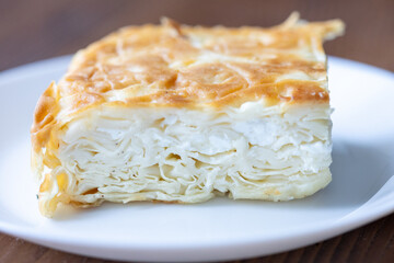 Traditional Turkish Cheese “Su Böreği” on a White Plate on a Brown Table