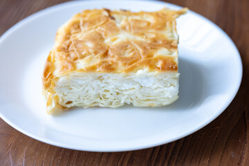 Traditional Turkish Cheese “Su Böreği” on a White Plate on a Brown Table