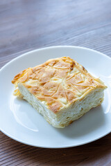 Traditional Turkish Cheese “Su Böreği” on a White Plate on a Brown Table