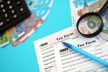 Kuwaiti dinar money bills and calculator with tax form on blue. Taxation and accounting concept