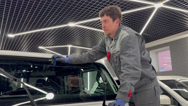 Automobile special workers replacing windscreen or windshield of a car in auto service station garage. Glass of the car, removed with the help of professional suction cups. The process of car repair. 