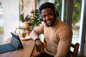 Freelancer using digital tablet to communicate online. He is sitting in bar and having video call.
