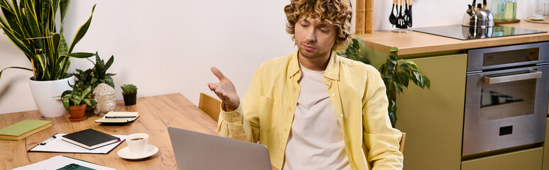 Handsome man in casual attire engaged with his laptop in a cozy kitchen setting