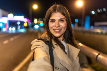 Woman smiling taking selfie at city street night