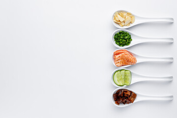 White spoons with sushi ingredients - salmon, cream cheese, isolated on a white background