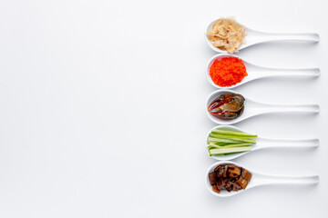 Sushi ingredients in white spoons on a white background. Eel, crab, mango, cream cheese