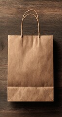 A simple, light brown paper shopping bag sits atop a wooden surface.  The bag has two handles