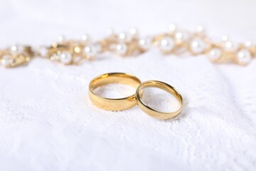 Beautiful golden rings and other jewelry on lace fabric, closeup