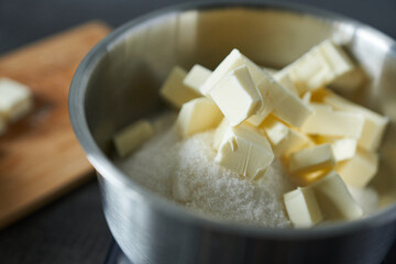 Sugar cubes and butter in bowl on wooden table, closeup