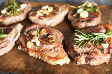 Grilled steak with garlic and rosemary on wooden board, closeup