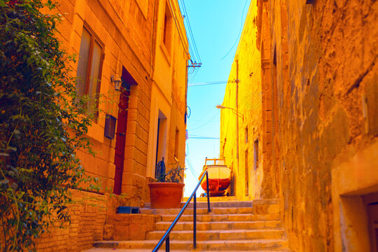 Narrow alleyway in Mdina, Malta, with ancient stone buildings and charming staircase leading upwards. Historical depth make it perfect choice for travel publications seeking evocative European imagery