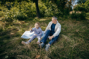 Fototapeta premium Adult father and little daughter are walking in the park