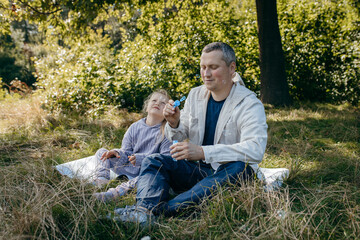 Adult father and little daughter are walking in the park