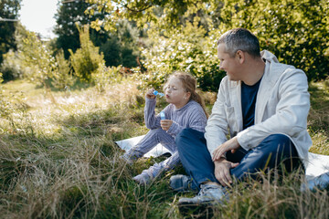 Adult father and little daughter are walking in the park