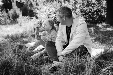 Adult father and little daughter are walking in the park