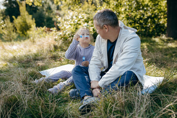 Adult father and little daughter are walking in the park