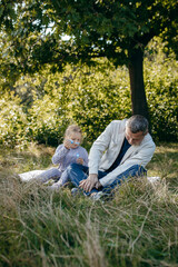 Adult father and little daughter are walking in the park