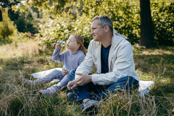 Adult father and little daughter are walking in the park