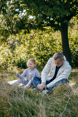 Adult father and little daughter are walking in the park