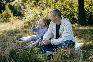 Adult father and little daughter are walking in the park