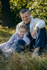 Adult father and little daughter are walking in the park