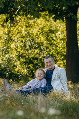 Adult father and little daughter are walking in the park