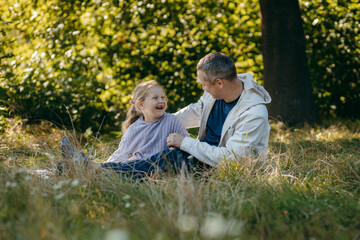 Adult father and little daughter are walking in the park