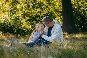 Adult father and little daughter are walking in the park