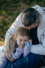 Adult father and little daughter are walking in the park