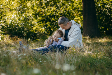 Adult father and little daughter are walking in the park